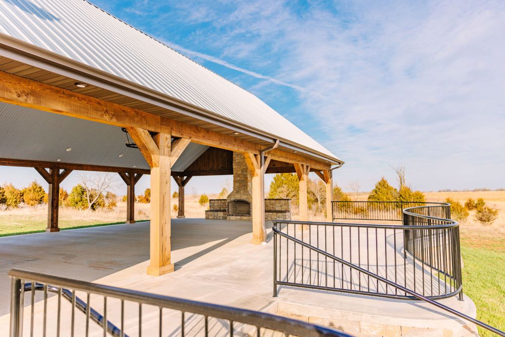 Modern covered pavilion with wooden posts and metal railings overlooking a scenic outdoor space.