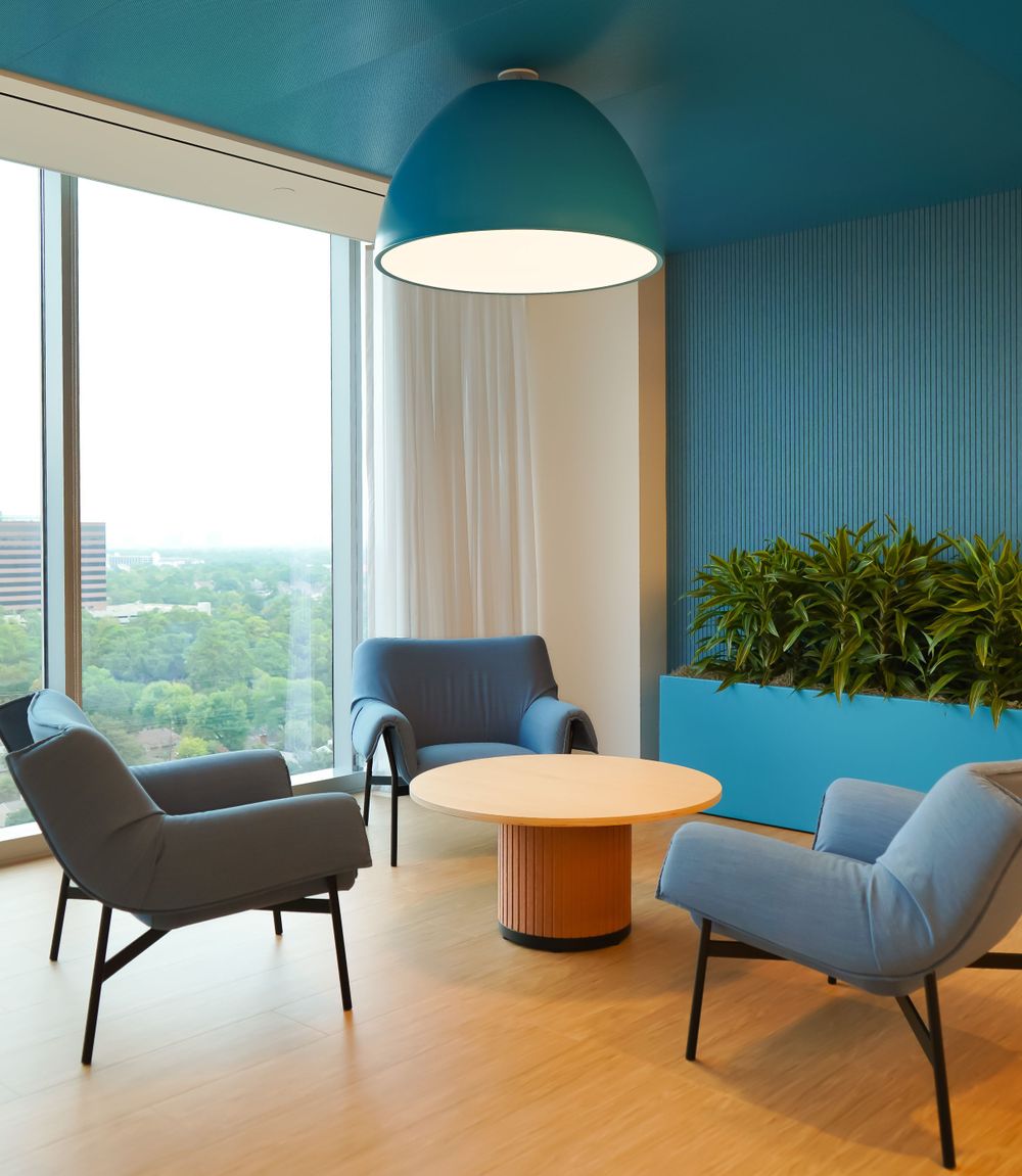 Modern lounge area with blue dome light, grey chairs and panoramic windows.
