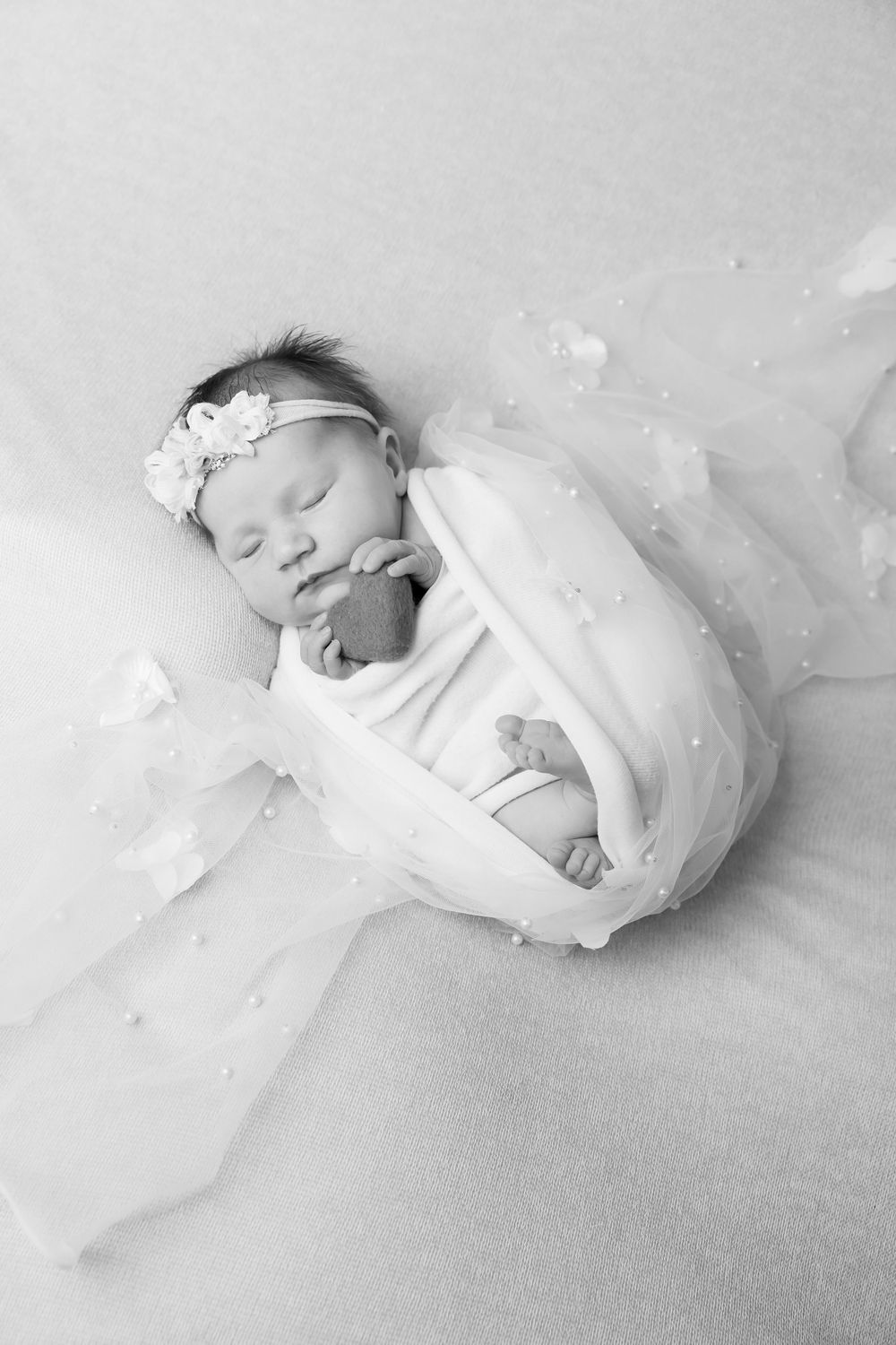 Black and white portrait of peaceful sleeping newborn with floral headband.