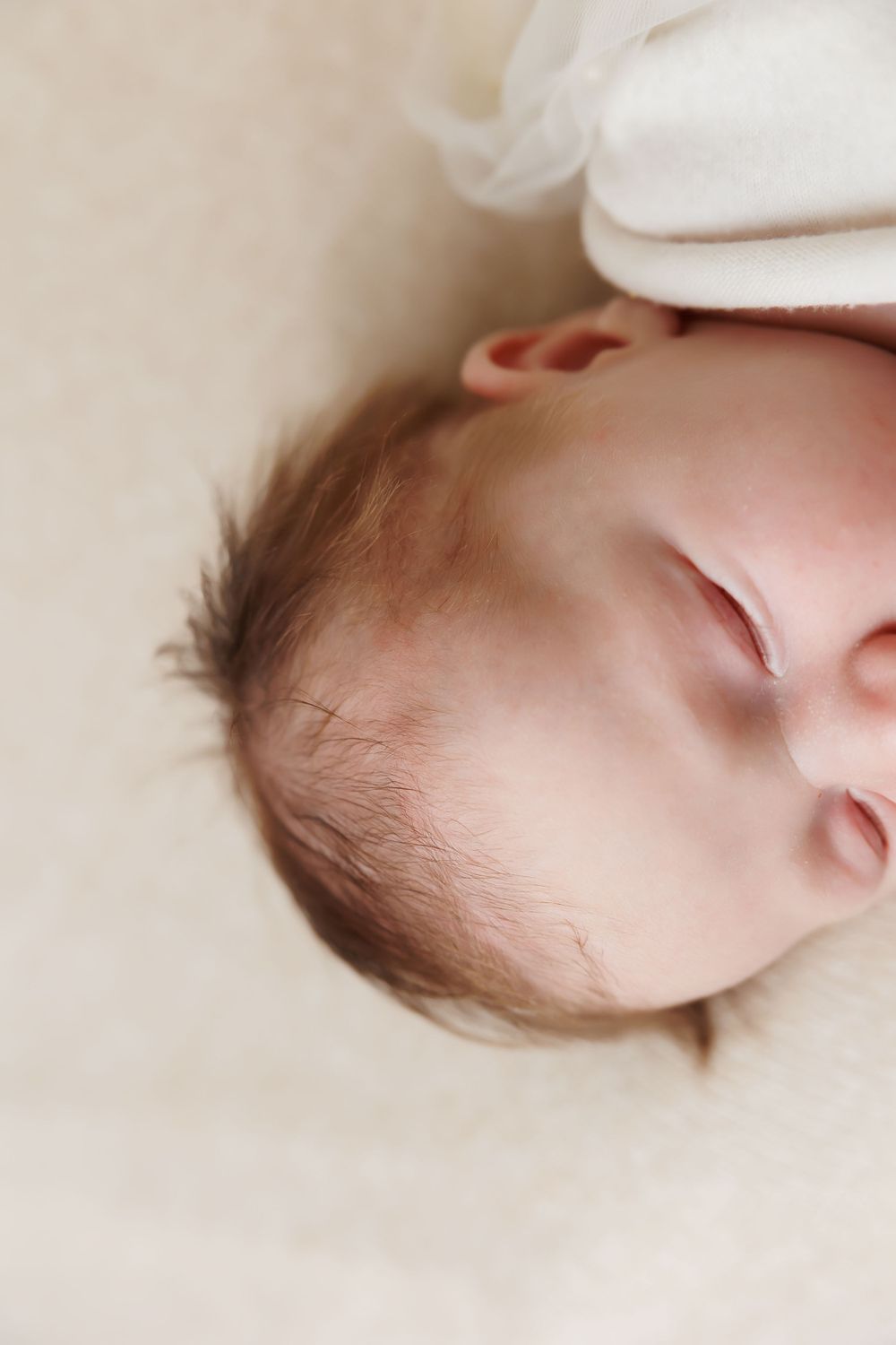 Close up of sleeping baby's face against cream colored background.