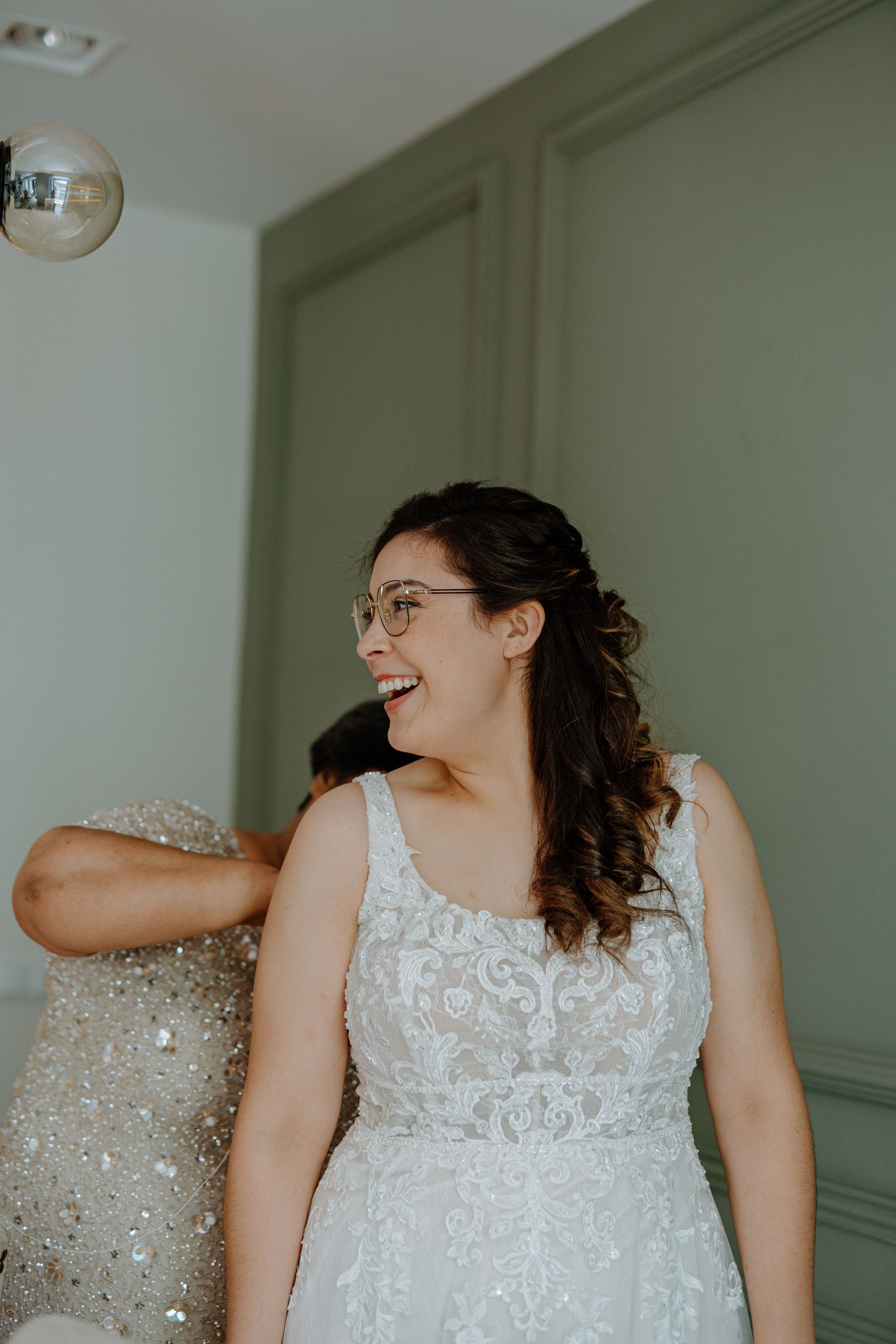 A joyful moment captured of someone wearing an elegant white lace wedding dress with delicate beading details.