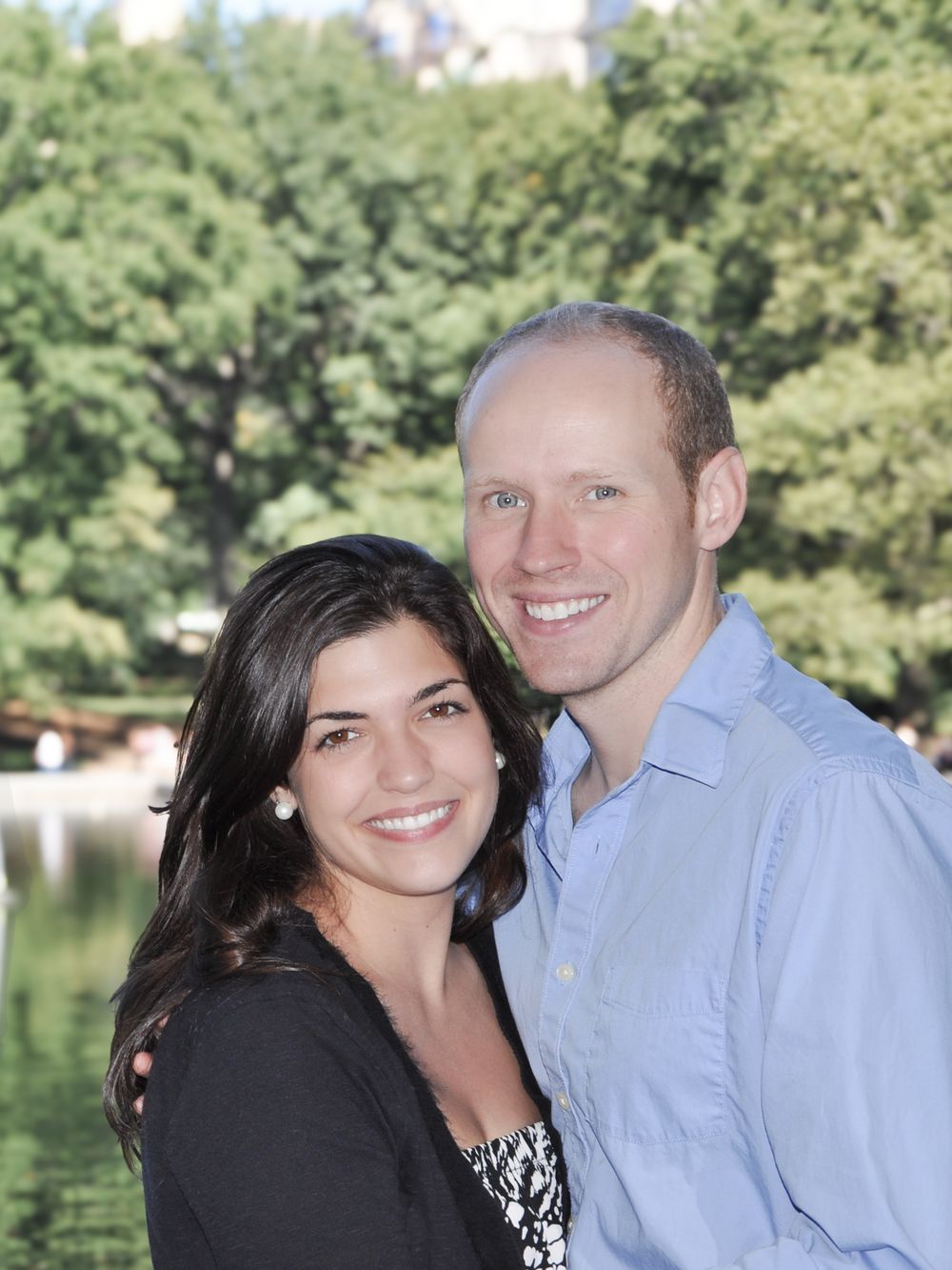 Engaged couple embracing near the Sailboat Pond in Central Park, with soft natural light highlighting their connection