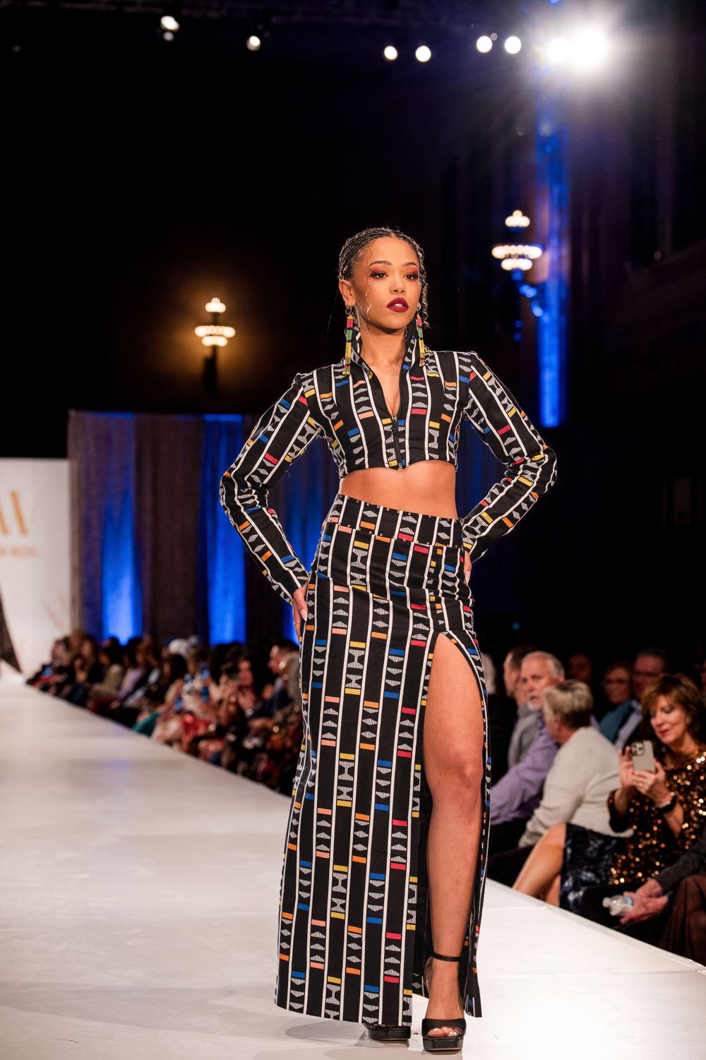 Bold geometric print coat with high slit design showcased on fashion catwalk.