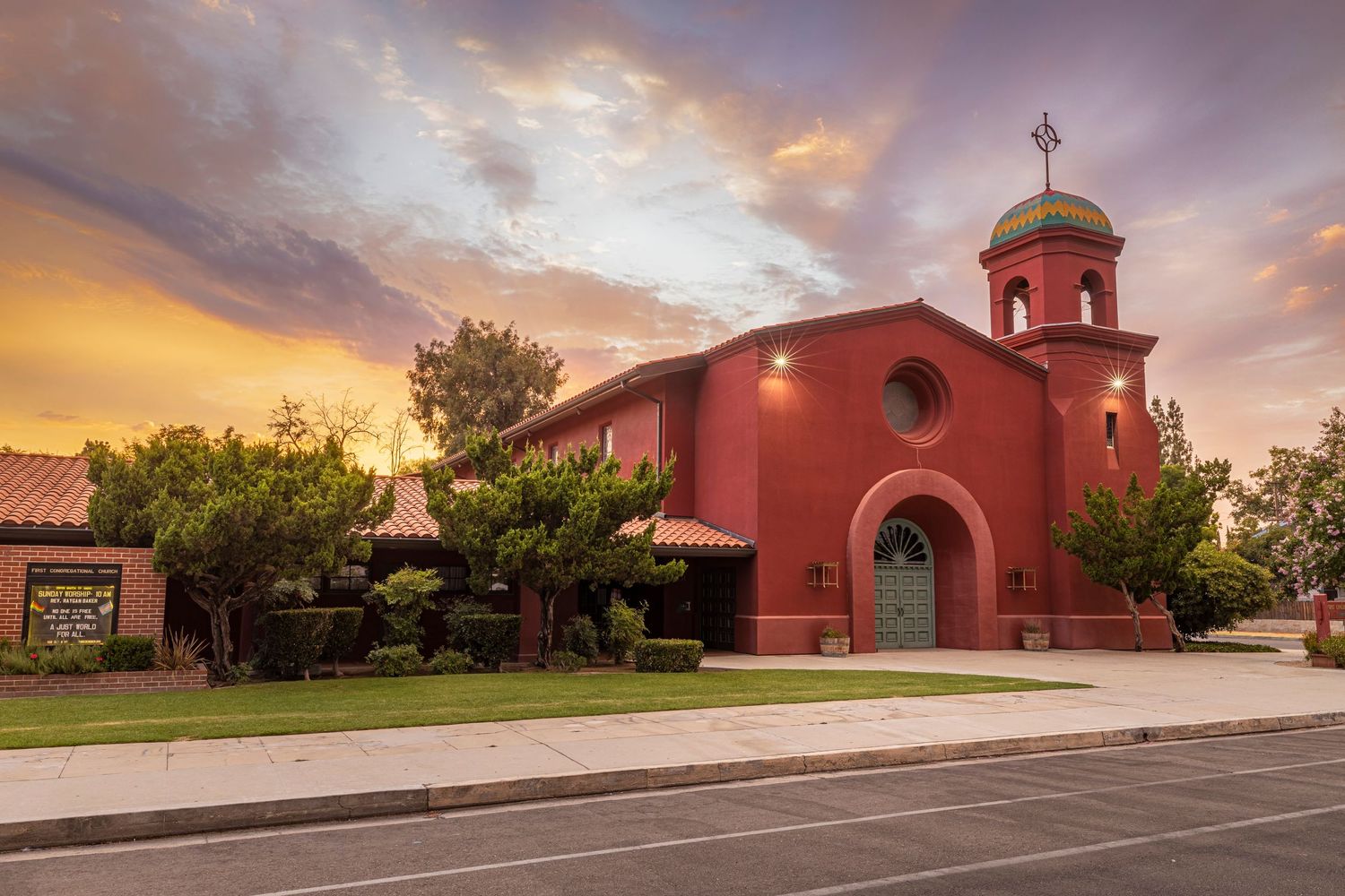 Beautiful red Spanish mission style church at sunset with dramatic sky.