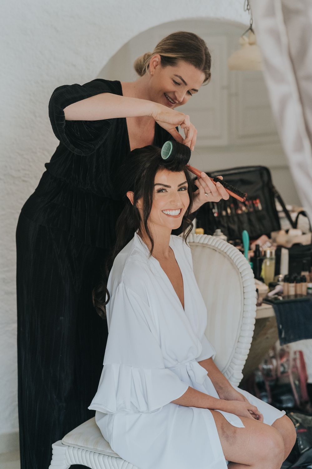 Getting ready scene shows wedding day hair styling preparation in a bright white room.
