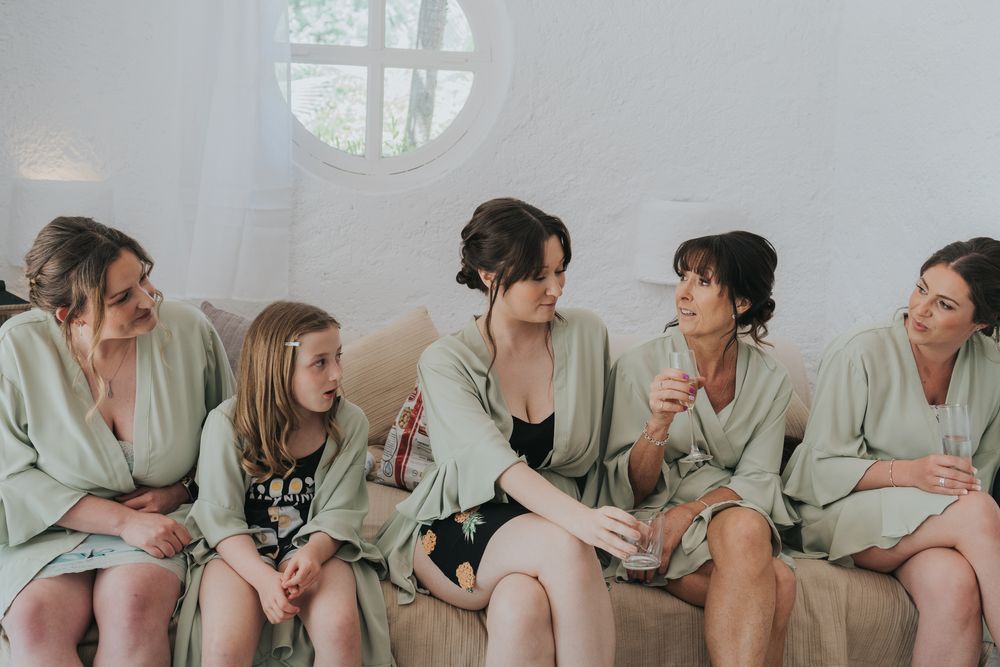 Bridal party in matching robes shares intimate conversation before the wedding ceremony.