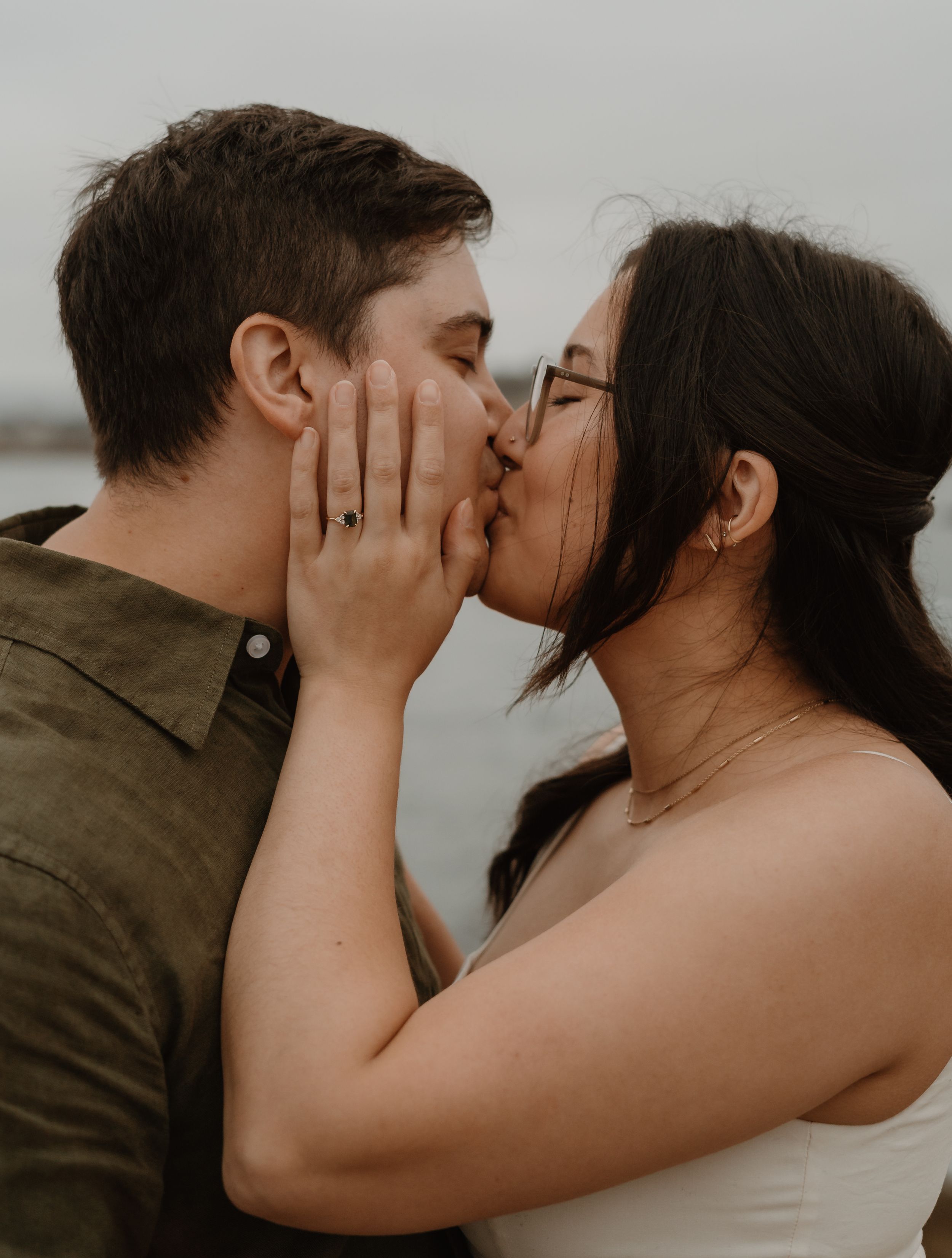 Two people sharing a tender kiss against a moody gray backdrop.