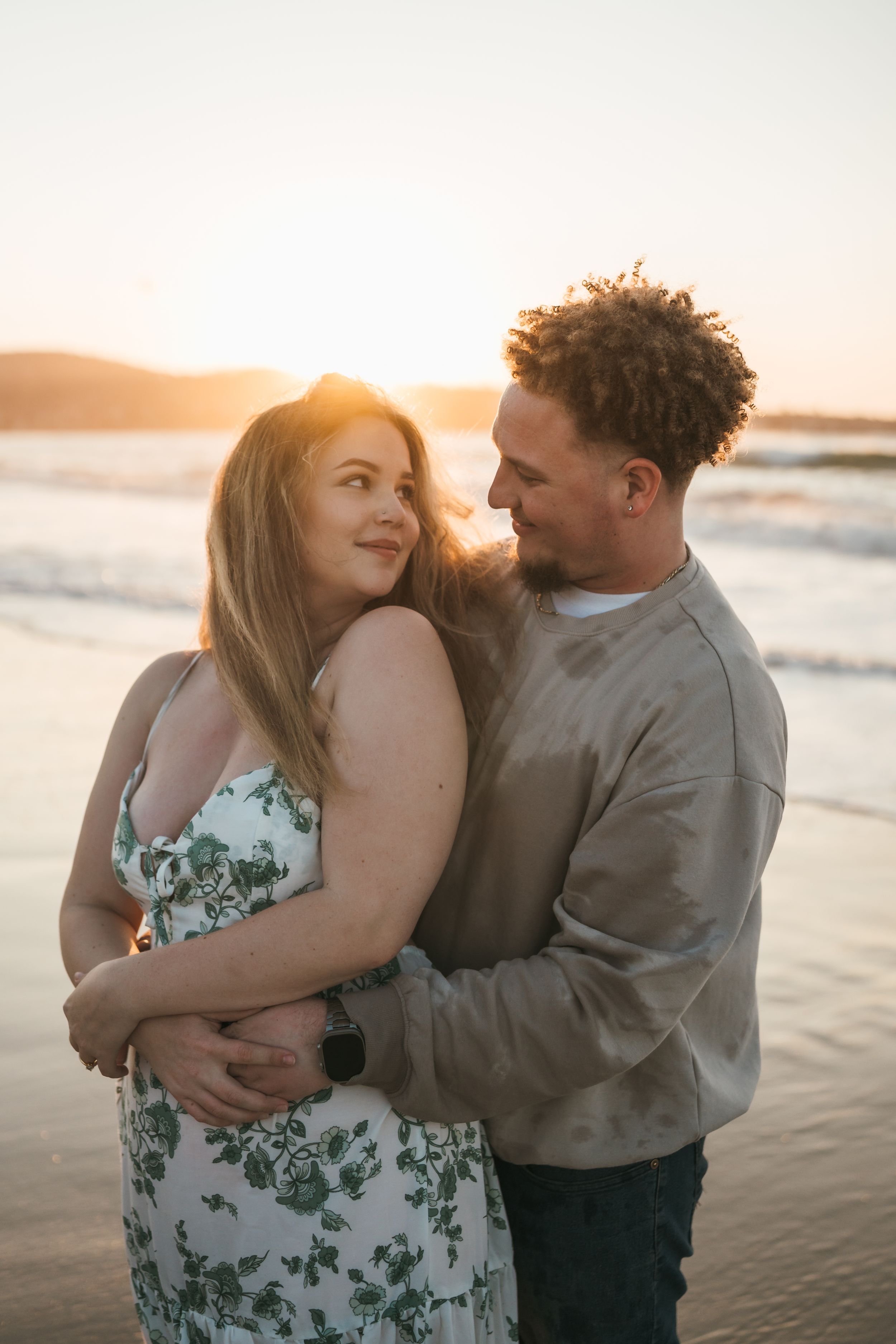 A romantic couple embraces on a beach at sunset in a series of intimate candid moments.