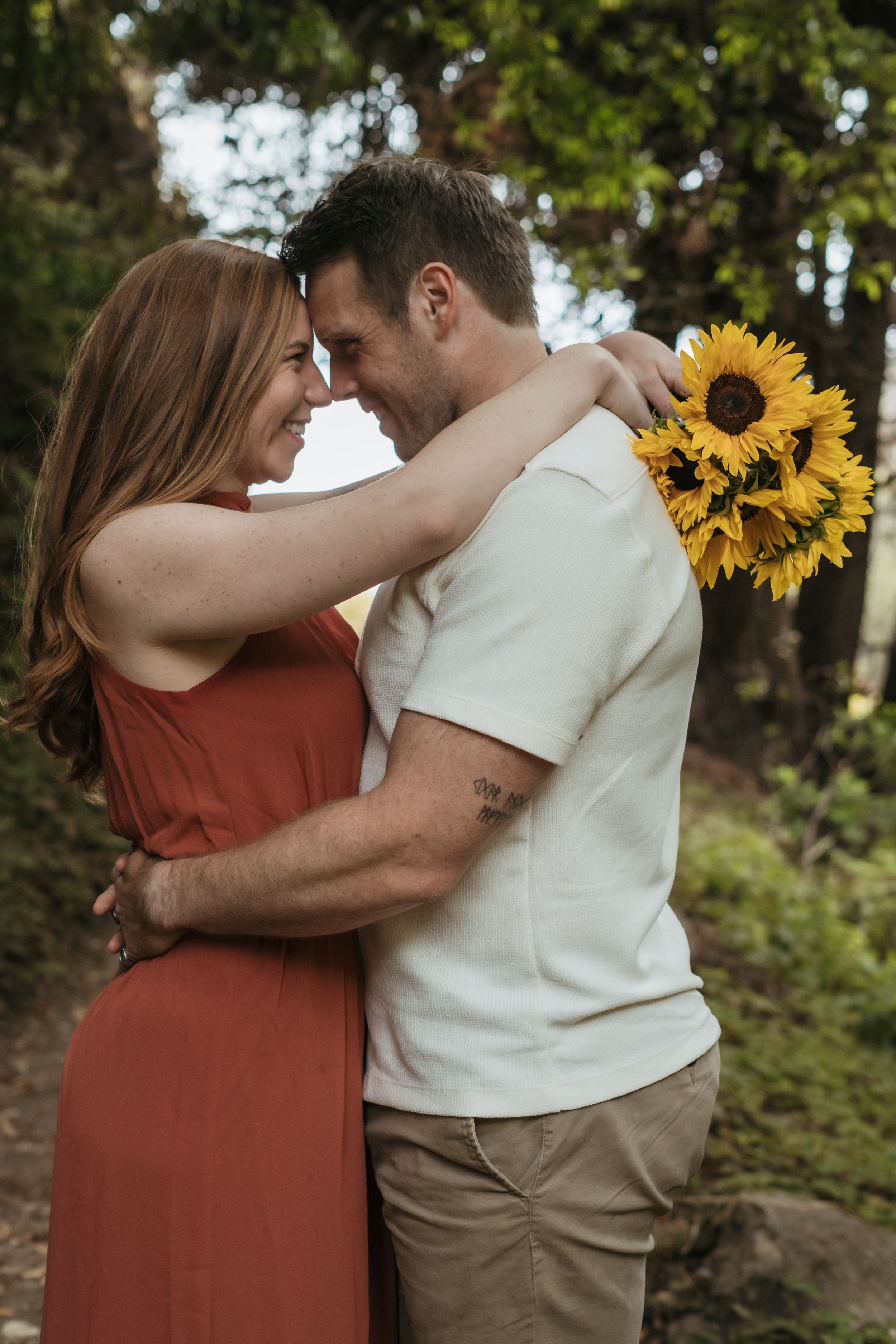 A couple embraces against a backdrop of sunflowers and nature in a romantic outdoor photo sequence.