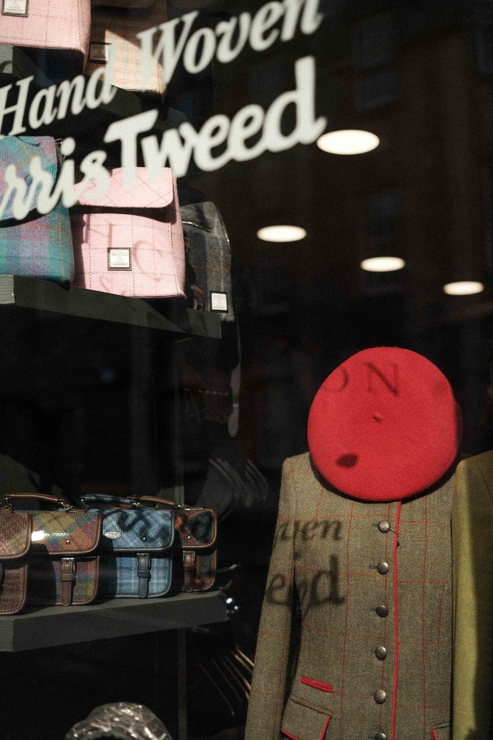 Shop window display featuring Harris Tweed clothing and a red beret.