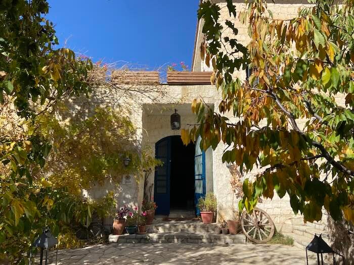 Mediterranean stone villa entrance with arched doorway framed by autumn leaves and rustic wagon wheel decor.
