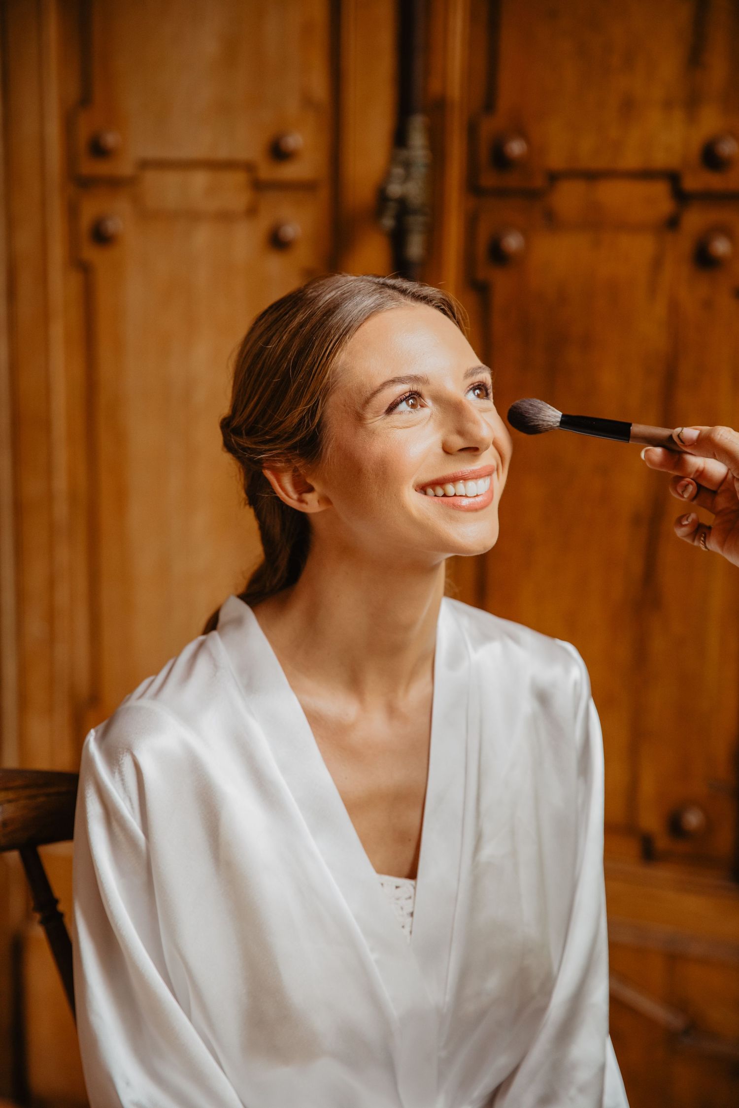 Getting ready shots of bridal makeup application in a rustic wooden room.