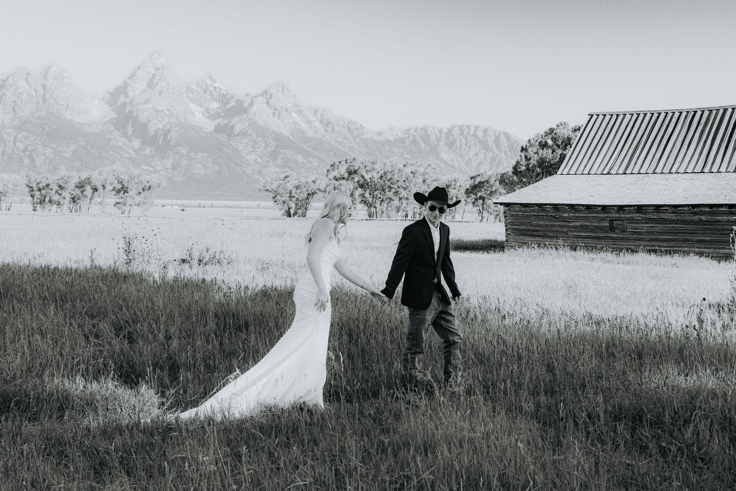 A romantic wedding portrait of a couple under flowing veil at sunset.
