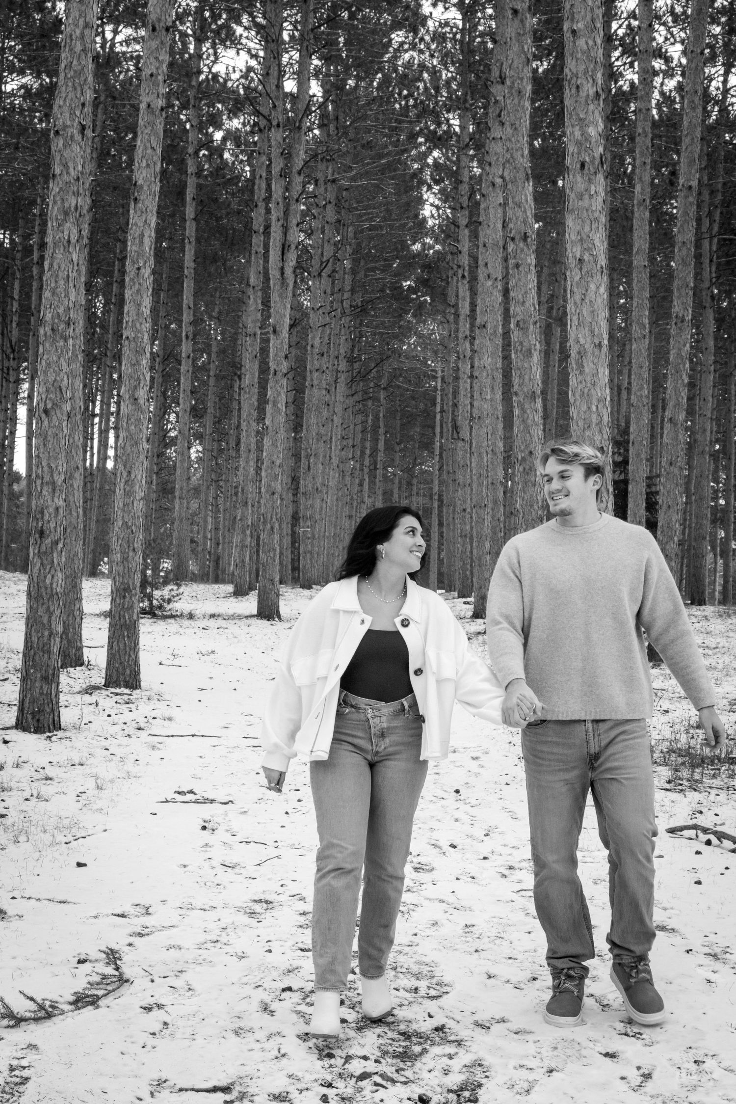 portrait of a young couple walking through the tree farm on a winter day