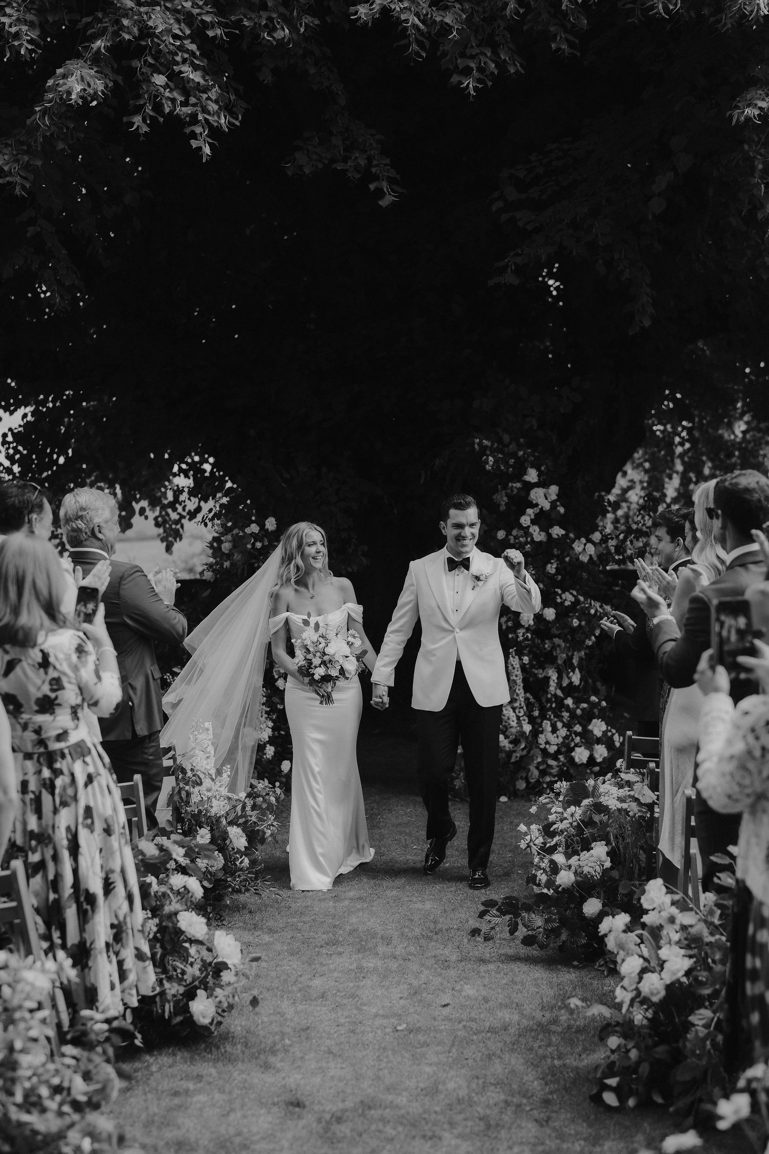 bride and groom walking down aisle cheering during ceremony at Hamswell house in bath