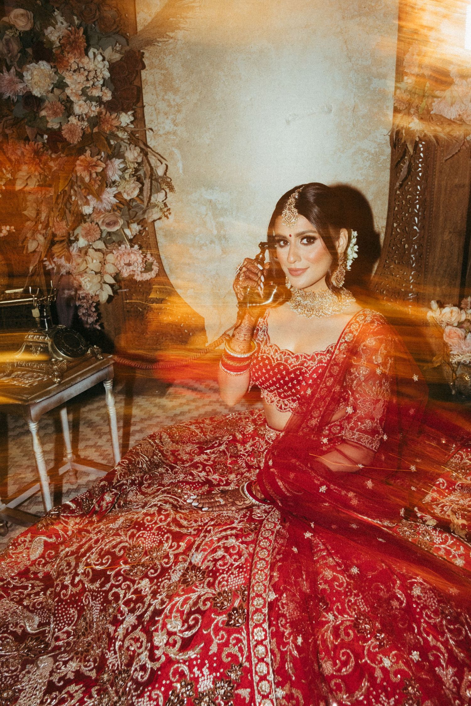 Beautiful traditional Indian bridal lehenga in deep red with intricate gold embroidery photographed in warm lighting.