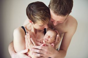 Mother and father snuggling their newborn in a cozy indoor setting, taken by Phoebe Lee Photo in Toronto