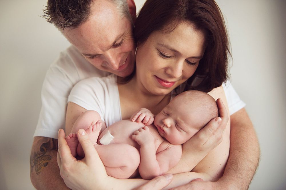 Parents holding their nude newborn baby close, photographed by Phoebe Lee Photo during a Toronto lifestyle session
