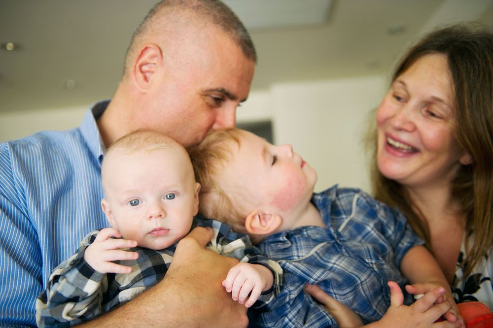 Parents with a baby and toddler smiling together at home, captured by Phoebe Lee Photo in Toronto