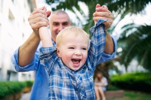 Dad holding his laughing toddler son overhead in a family session by Phoebe Lee Photo, taken in an outdoor setting