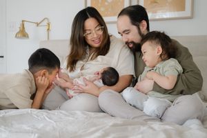 Family laying together in bed sharing tender moments with their newborn baby. Family newborn lifestyle photo session by Phoebe Lee Photo GTA