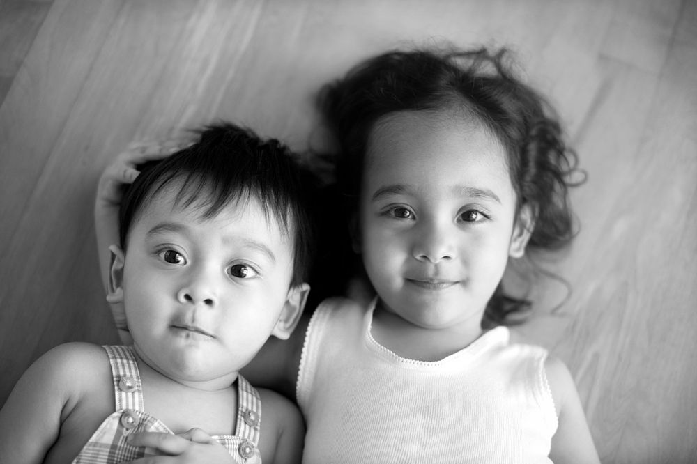Two siblings resting side by side in a black-and-white portrait, photographed by Phoebe Lee Photo in Toronto