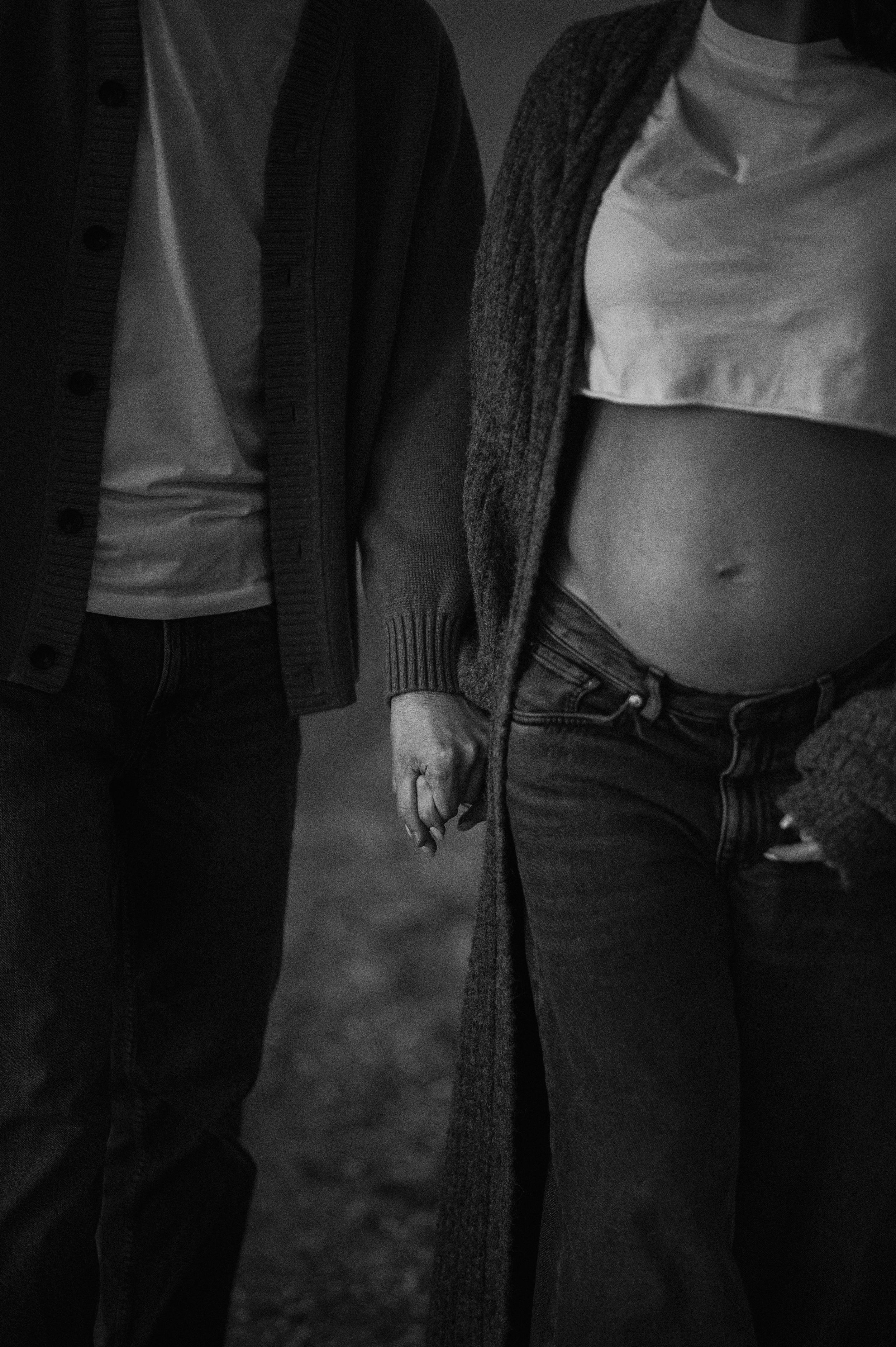 Close-up of two people holding hands while wearing casual clothing.