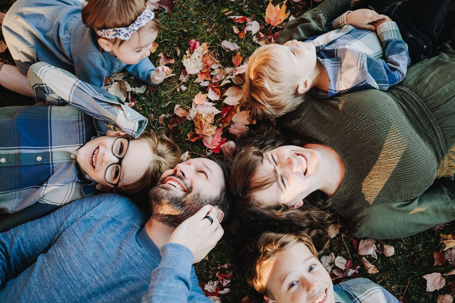 Family Photographer | Plymouth, Michigan | Newborn Session | Kids | Family lying on ground surrounded by autumn leaves