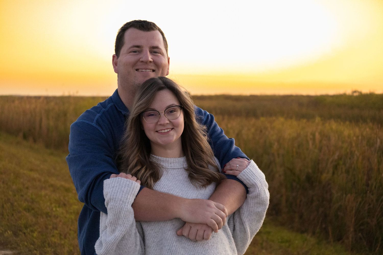 Golden sunset photoshoot in tall grass field during magic hour.