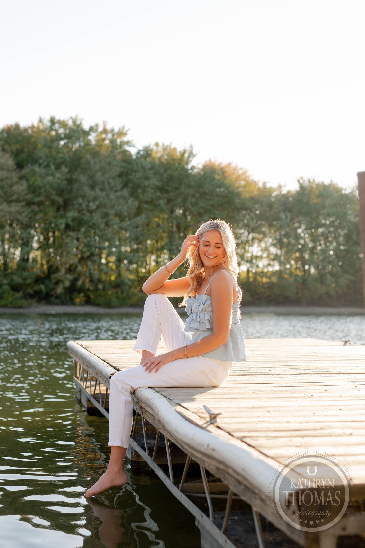 Relaxed summer portrait on wooden dock with lake and forest backdrop.