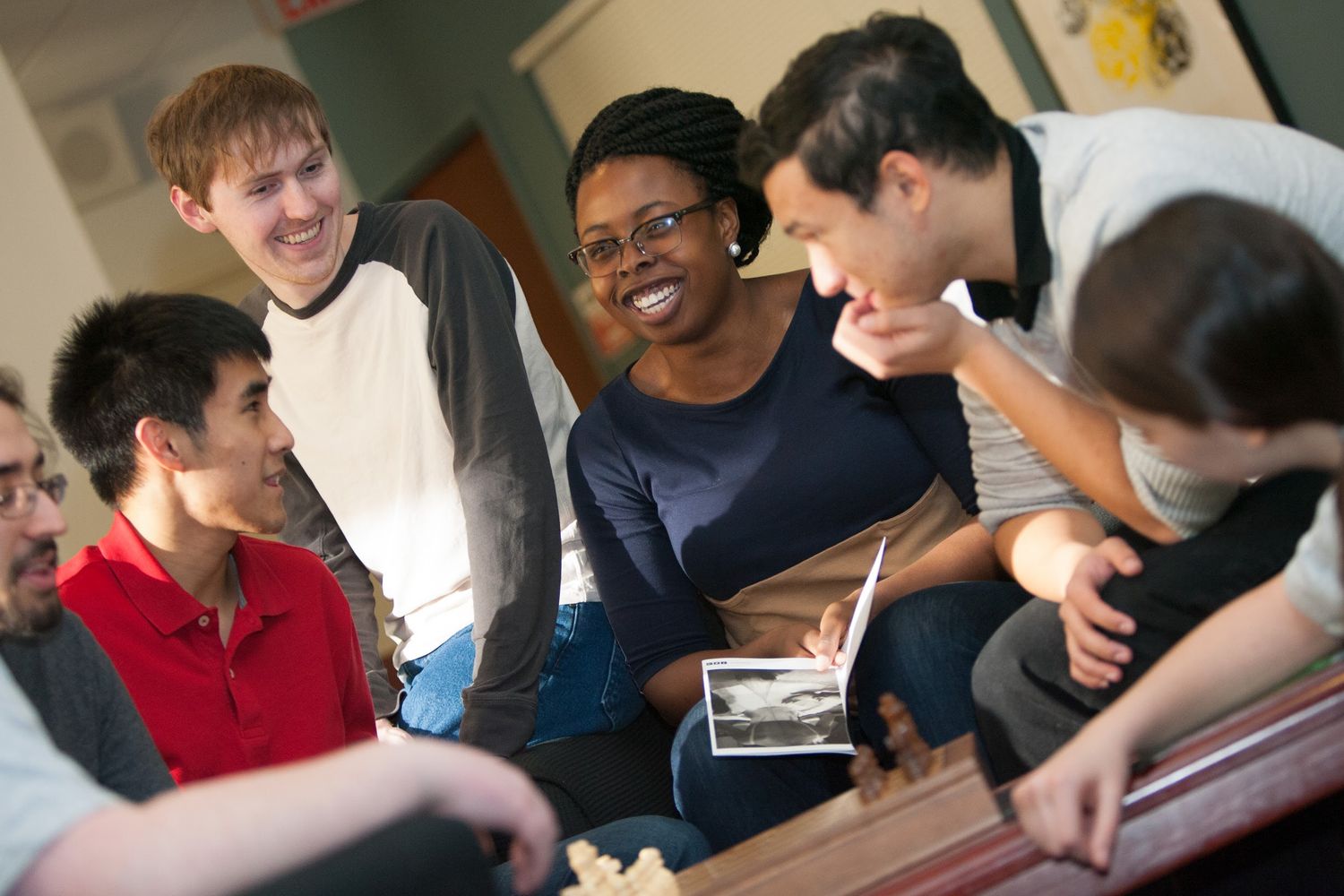 A diverse group of students laughing and socializing together in a casual study environment.