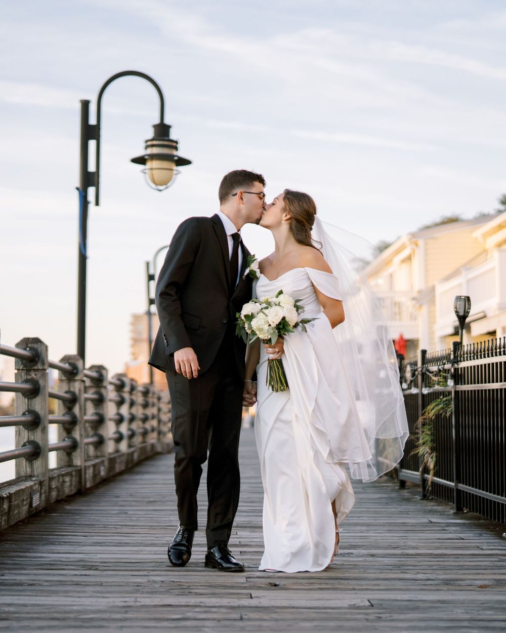A romantic moment between newlyweds on a wooden pier with vintage lighting.