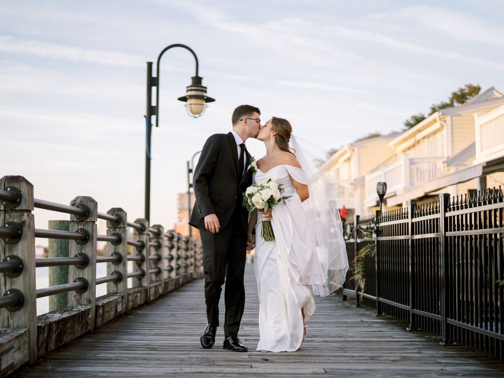 A couple shares a tender moment on a boardwalk during their wedding photoshoot.