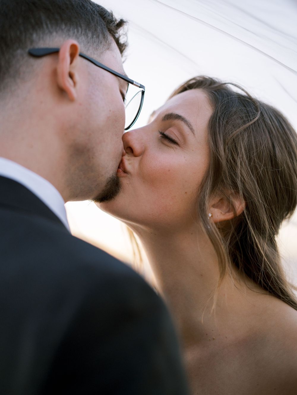 A romantic wedding kiss photographed in closeup with natural lighting.