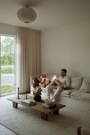 Serene modern living room with minimalist decor featuring a plush sofa, wooden coffee table and large windows.