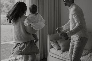 A family having fun in their bedroom jumping on the bed together in a candid black and white moment.