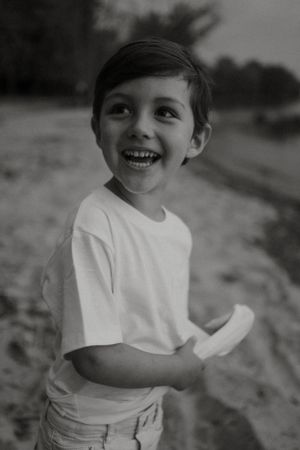 Black and white candid portrait of child laughing on beach.