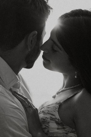 Intimate black and white portrait of couple about to kiss in romantic lighting.