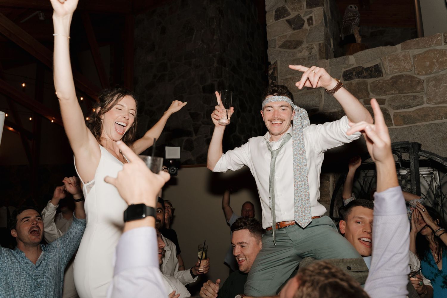 Wedding reception celebration with guests lifting the newlyweds up during an energetic dance party.