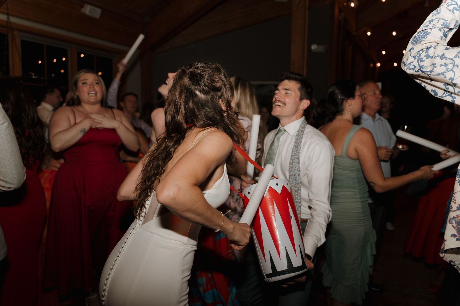 Dancing wedding guests celebrate on a crowded reception dance floor with festive energy.