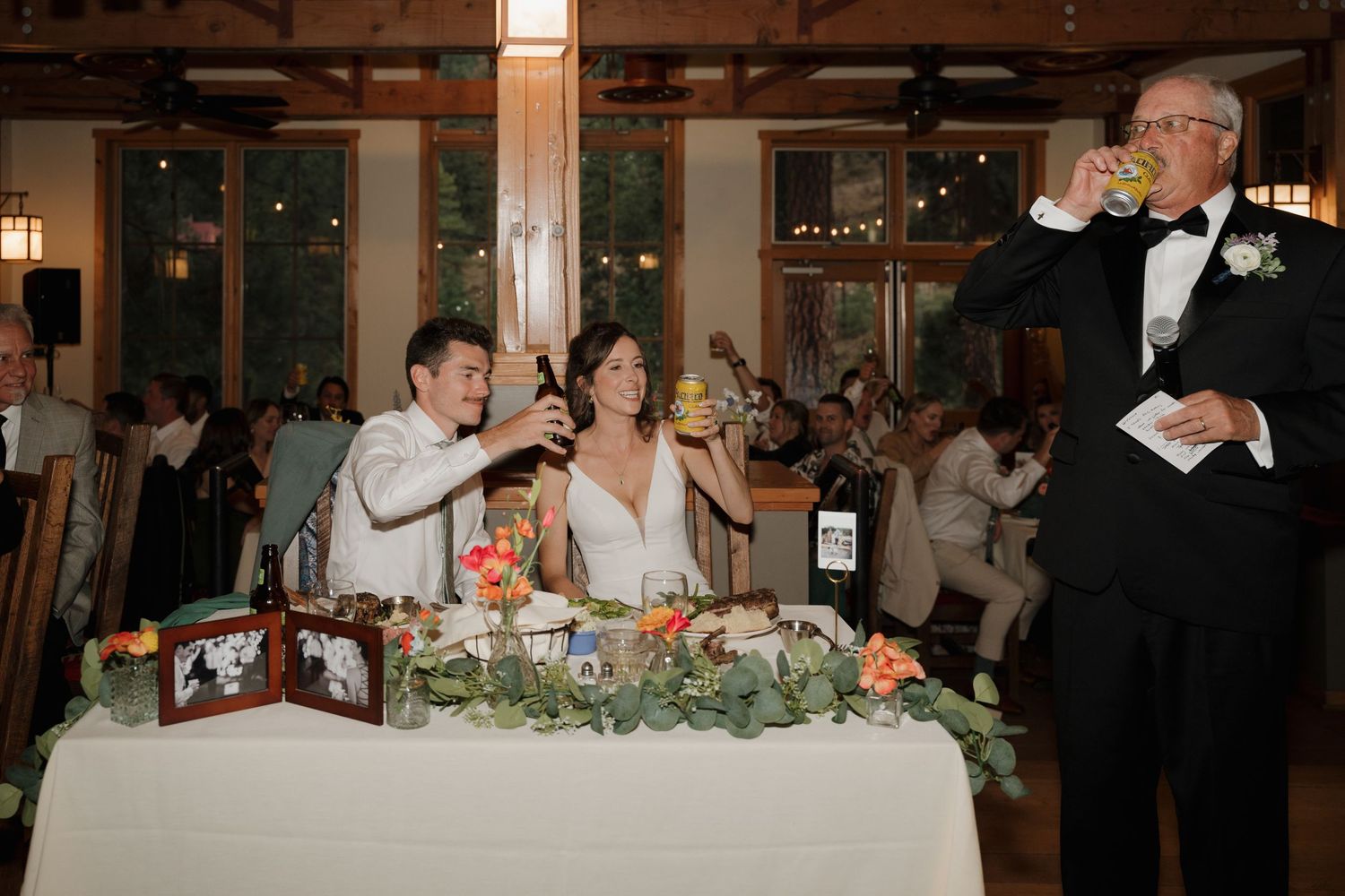 Wedding party toasts at head table decorated with greenery garlands.