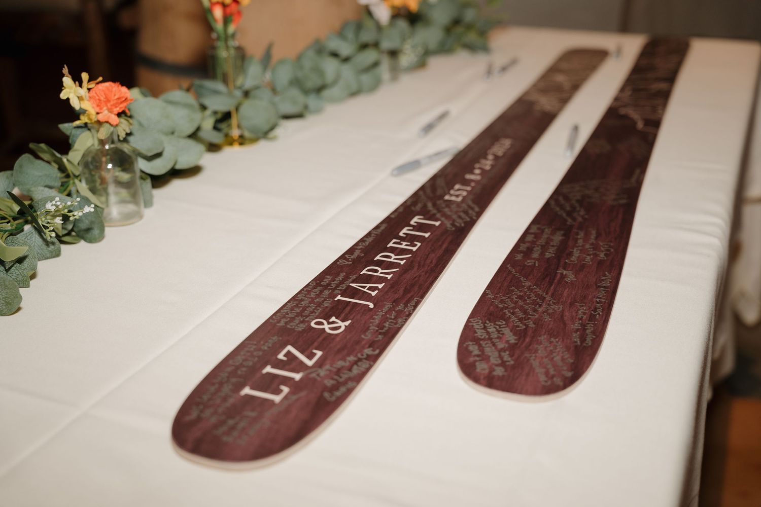 Custom wooden skis displayed as wedding decor with eucalyptus accents.