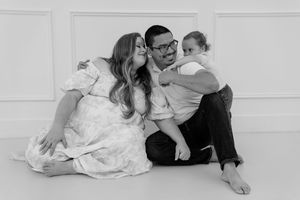 Black and white photo series showing couple in casual poses laying and sitting on white floor.