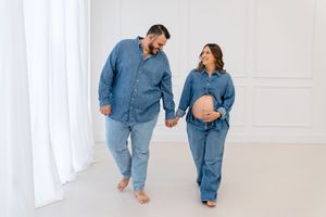 Family in matching denim outfits walk together down bright white hallway in playful candid moment.