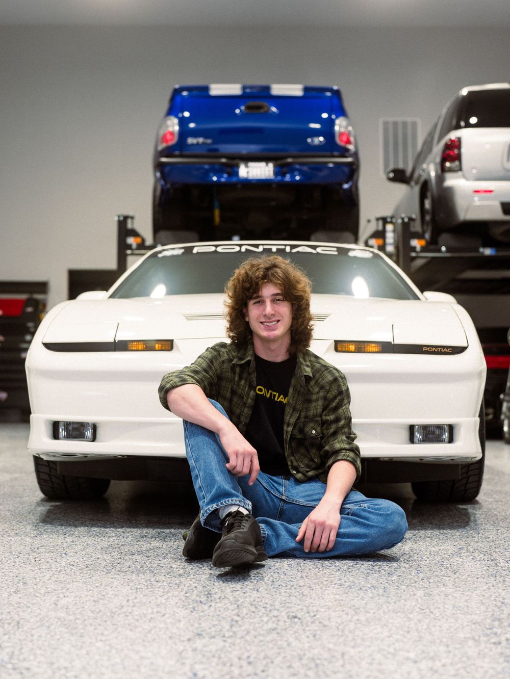 A vintage white Pontiac sports car with pop-up headlights in an indoor garage setting.