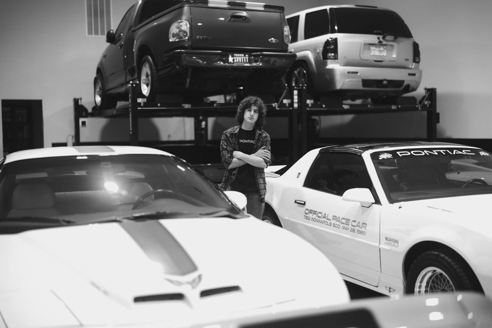 A white classic Pontiac Firebird Trans Am displayed in an indoor showroom setting.