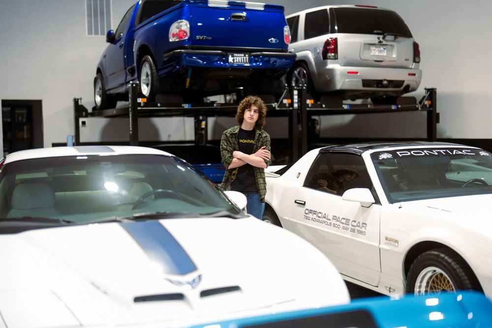 Professional photo of white Pontiac sports cars in a garage workshop environment.