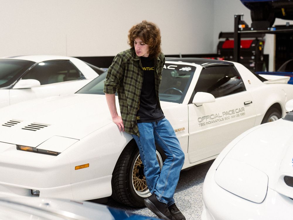 Classic white Pontiac Trans Am sports car with a fan posing in a garage collection.