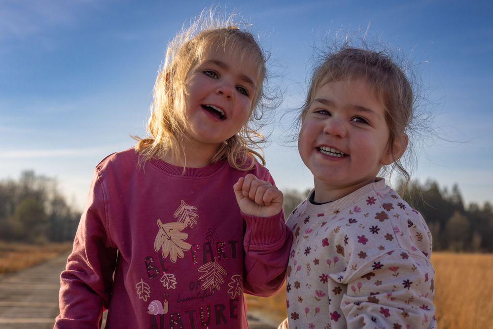 Two children in warm clothing share a joyful moment outdoors.
