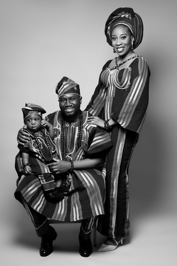 A black and white portrait of a family wearing traditional African attire with matching striped patterns.